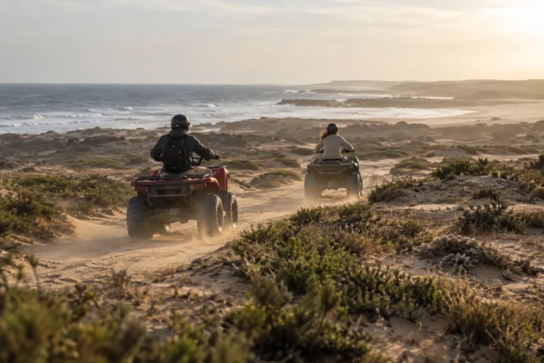 Deux quads sur une piste de sable entre les dunes, l'océan à l'horizon